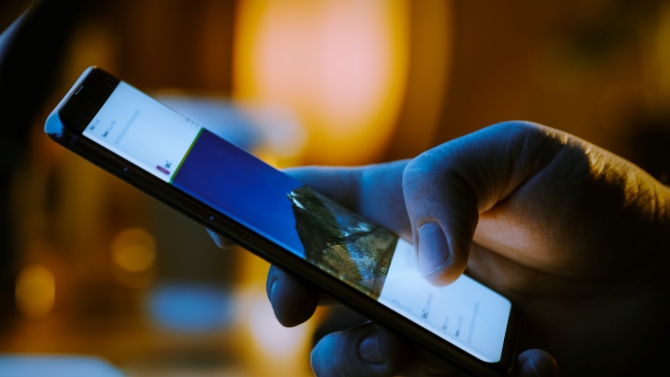 Person Holding and Using Smartphone, Browsing through Pictures on Social Network Wall