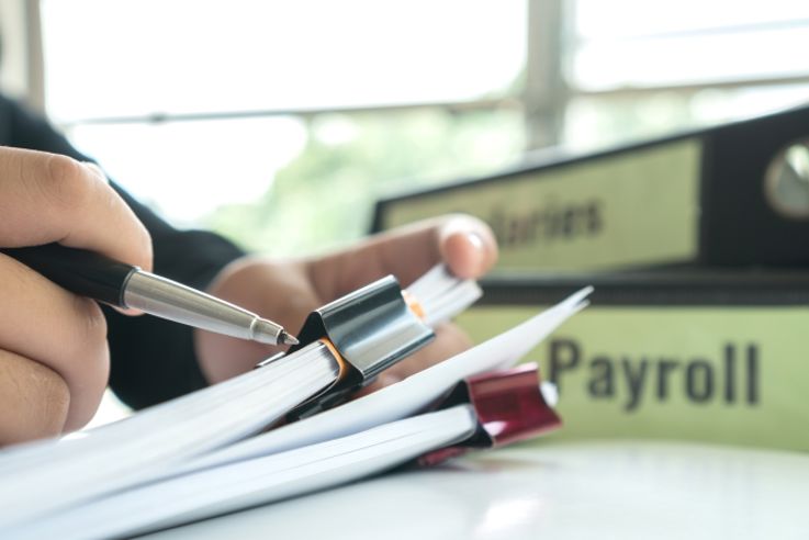 Businessman manager hands holding pen for reading, signing paperwork near payroll salary binder, 